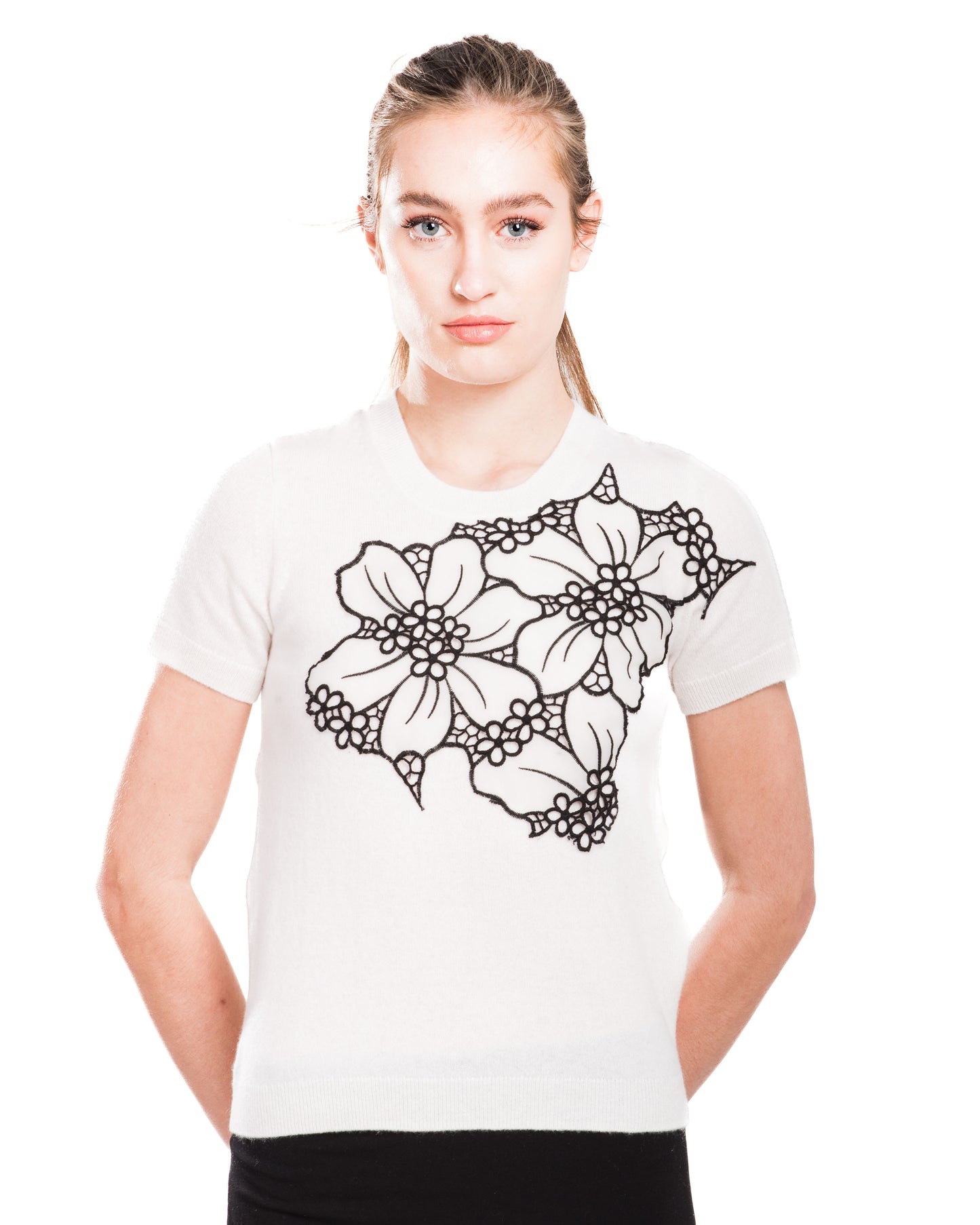 SMALL WHITE CREW NECK SHORT SLEEVE CASHMERE SWEATER WITH APILQUED FRONT WHITE SILK ORGANZA FLOWERS W BLACK OVERSTITCHED TRIM & PETITE FLORAL CUTOUTS